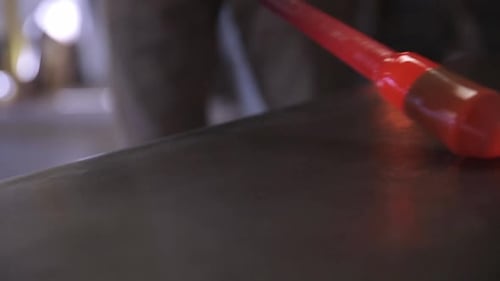 Glass Blower Shaping Molten Glass on Table