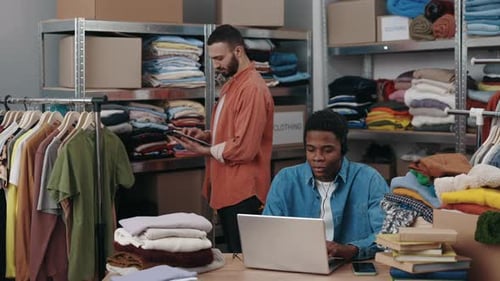 Multiethnische Menschen, die in einem Bekleidungsgeschäft arbeiten, sammeln Bestellungen für den Versand an den Kunden ab
