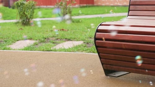 Colorful Bubbles Drift Near Park Bench With Greenery Background