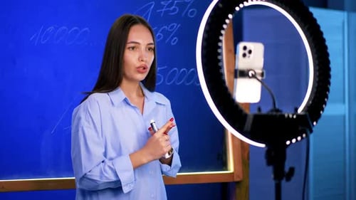 Woman Explains Financial Data in front of Blackboard