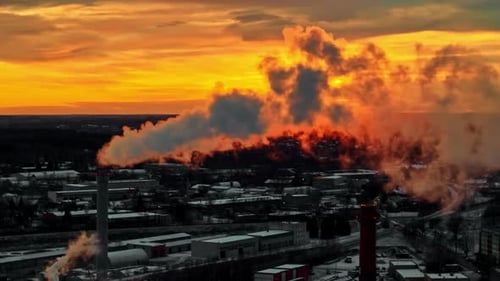 Cielo rojo al atardecer y chimenea humeante de la fábrica, vista aérea