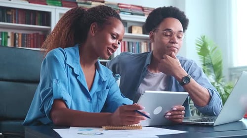 Young African American Woman and Man Office Workers Sits at Table with Papers