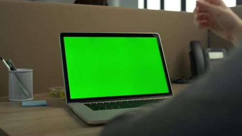 Unrecognizable businessman hands typing on green screen laptop at workplace