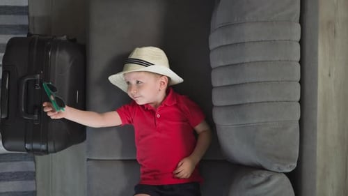 Boy on Couch Plays with Sunglasses Ready to Travel