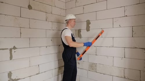 Man Checks Wall With Level Inside Building