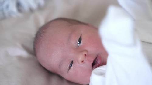 Gentle Newborn Baby Lying in Bed at Home