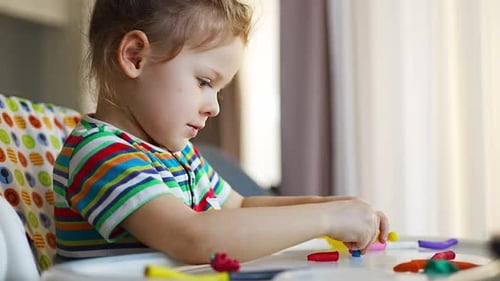 Child Plays with Clay at Table Indoors
