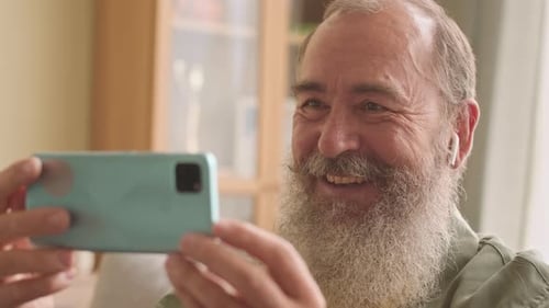 Senior Man Video Calling With a Smartphone Indoors