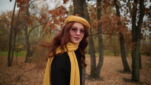 Elegant Lady Adjusts Hair in Autumn Park with Yellow Beret