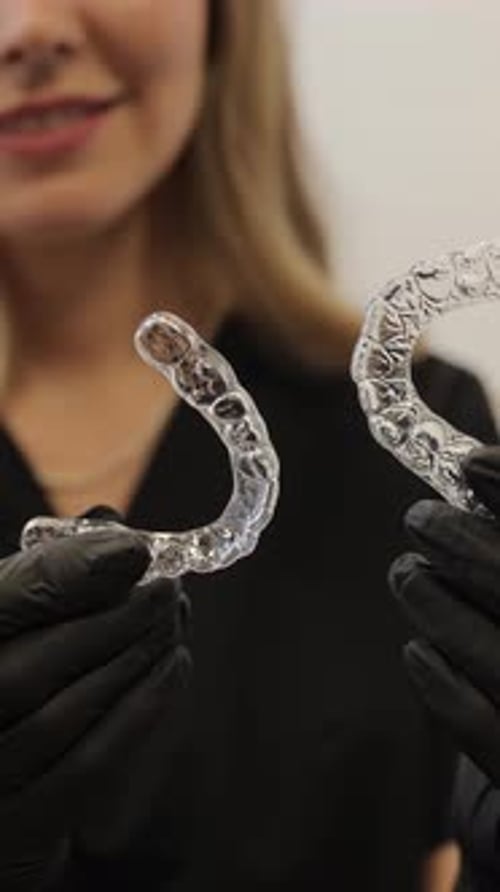 Woman Holding Clear Dental Aligners in Gloved Hands