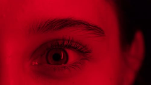 Young Girl Opens Her Big Eye In Red Light Close Up View