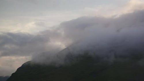 Clouds covering the mountain peaks with the sun shining over the clouds