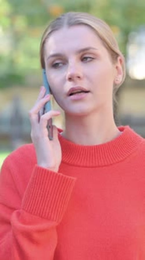Woman in Orange Sweater Talking on Her Mobile Phone