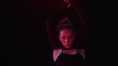 Woman Dancing in Red Lit Dark Space