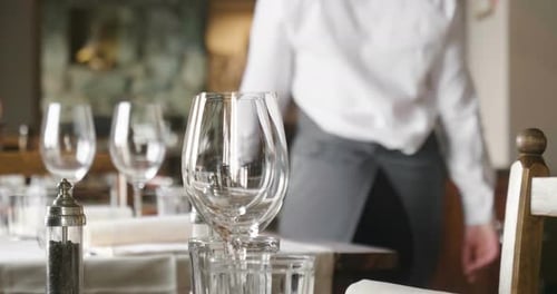 Un camarero pone la mesa en un restaurante antes de que lleguen los clientes y utiliza cubiertos y vasos finos