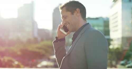 4k video footage of a handsome young businessman talking on the phone while walking in the city