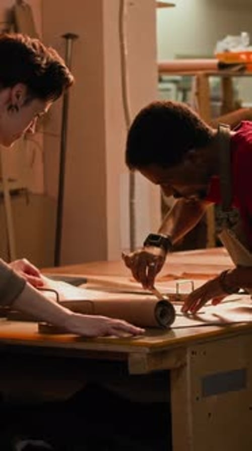 Vertical of Young Multiethnic Artisans Cutting Leather Details in Workshop