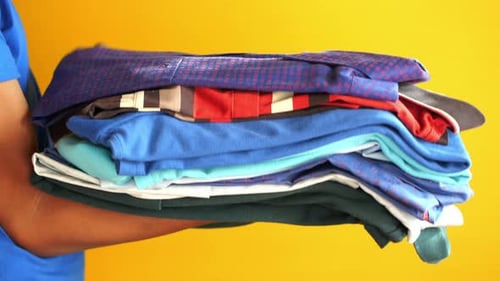Folding Colorful Shirts in a Stack on Yellow