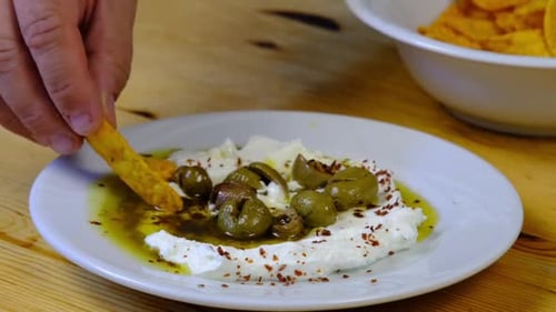 the chef dips chips into yogurt sauce