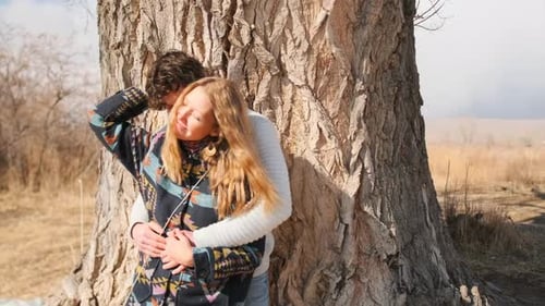 Affectionate Couple Embracing by Tree in Rural Field