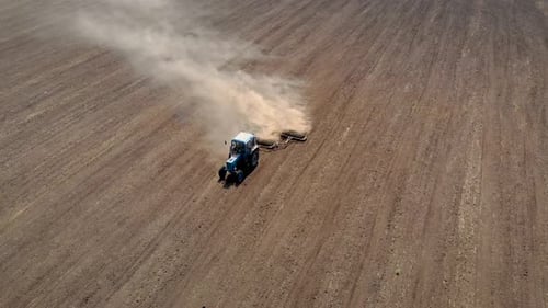 Aerial View Farm Tractor with Disk Harrow on Dusty Field Preparing Soil for Sowing Crops