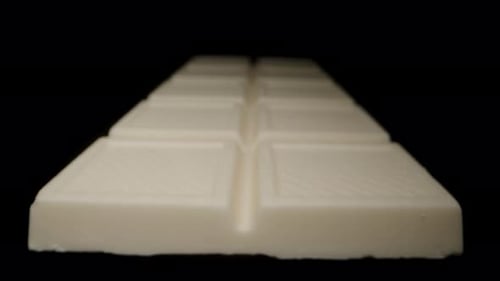 A white chocolate bar on a black background for cutout. Light illuminates it from different angles.