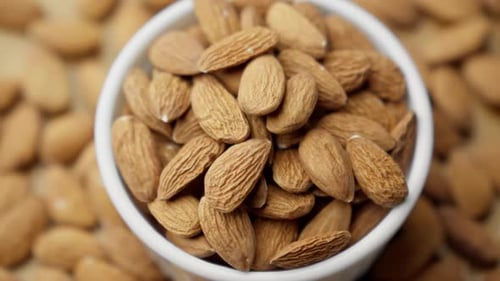 Almond Kernels in White Bowl Rotating Almonds Arranged in Pleasing Pattern