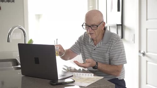 Senior Man Sorting Pills While Using Laptop