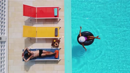 Aerial view of a sun-kissed couple enjoying a summer day in the pool