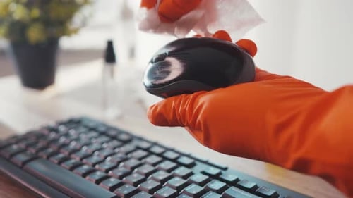 Close up of gloved hand cleaning computer mouse