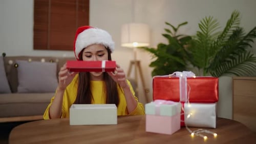 Woman in Santa Hat Opening Christmas Present