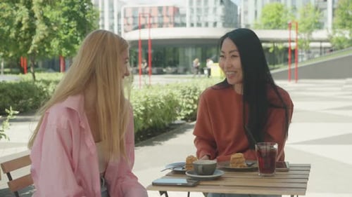 Two Young Women Chatting at Outdoor Cafe