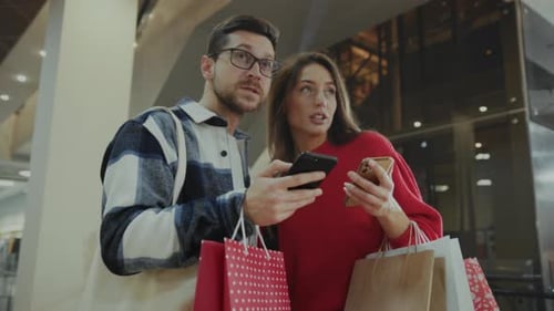 Man and Woman Exploring Shopping Offers Two Individuals Examining Online Promotions in Brightly Lit