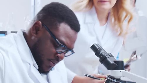 Scientists Work with Microscope in Modern Laboratory