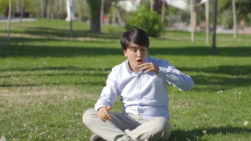 Man Coughing While Sitting on the Grass