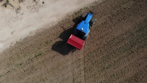 Blue Tractor Moves Through Dirt Field Aerial Shot