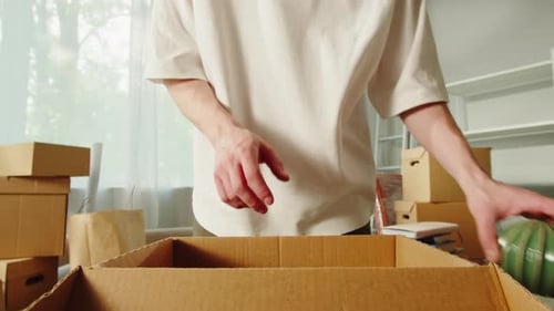 Young Adult Packing Household Items Into Box