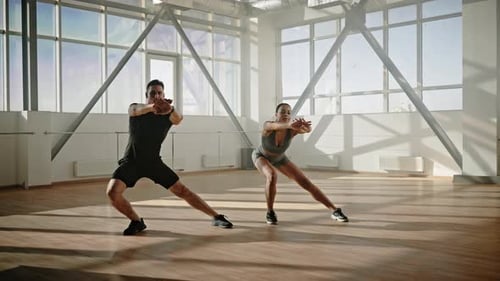 Athletic Man and Woman Warming up in Dance Studio