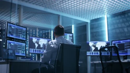 Dos ingenieros técnicos sentados en sus lugares de trabajo con varias pantallas. Están en Monitorin