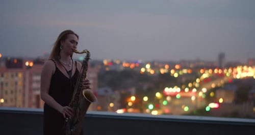 Woman Plays Saxophone on City Rooftop at Night