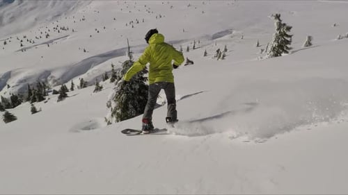 Snowboarder Snowboarding Down a Snowy Mountain in Winter