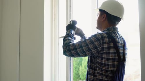 Construction Worker Installing Window with Drill