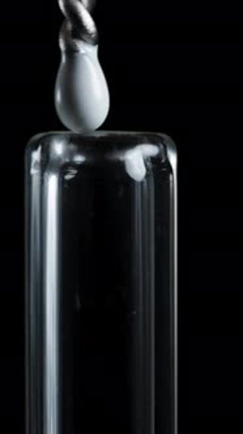 Vertical video. A cleaning brush inserted into a glass drinking straw. Macro shot on a black.