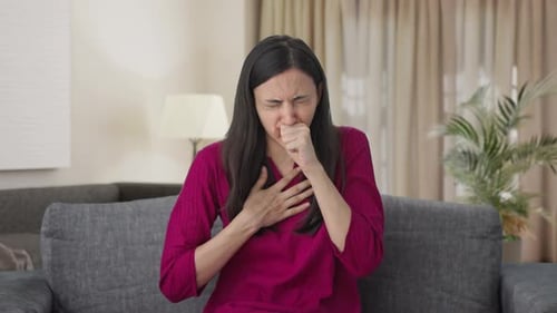 Woman Coughing on Couch Feeling Sick at Home