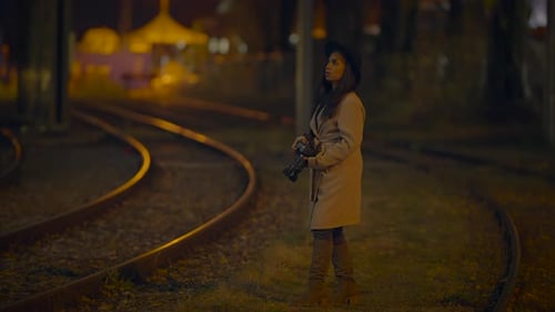 Woman Photographer with Camera Standing Near Railroad Tracks