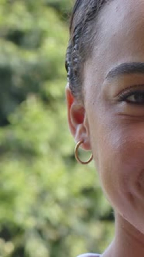 Vidéo verticale : tête inclinée, femme en plein parc souriante dans un haut à col et cerceau doré, espace de copie