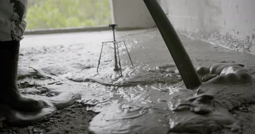 Close-up of liquid screed being poured onto a floor during construction