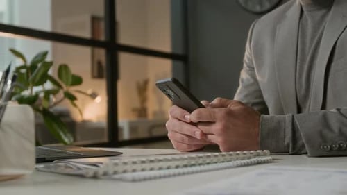 Hands of Unknown Businessman Using Internet on Smartphone Sitting at Work Table