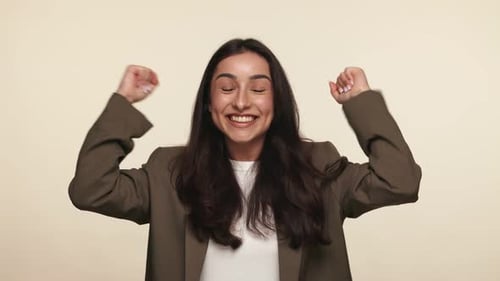 Excited Woman Celebrates with Arms Raised in Studio