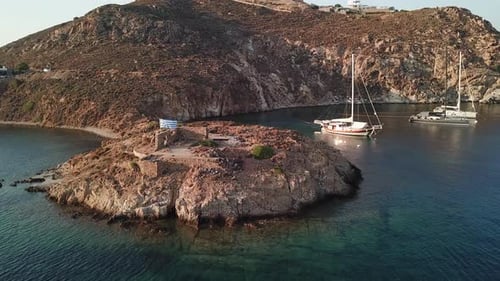 Grèce, île de Patmos, vue aérienne, entrée de la baie de Grikos, ruines d'une vieille maison et grand drapeau grec